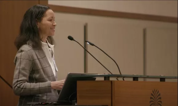 Woman in a suit smiling from a podium.
