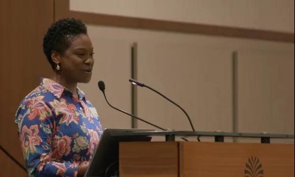 Woman smiling from a podium and speaking.