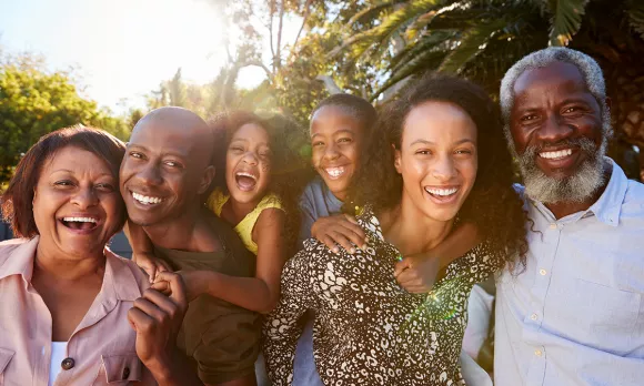 A family of six smiling and hugging looking at the camera 