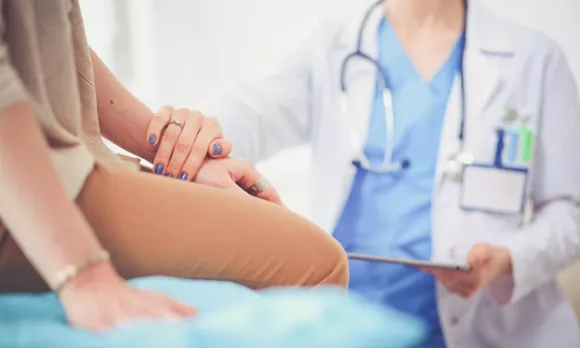 Physician placing a hand on her patient's arm.